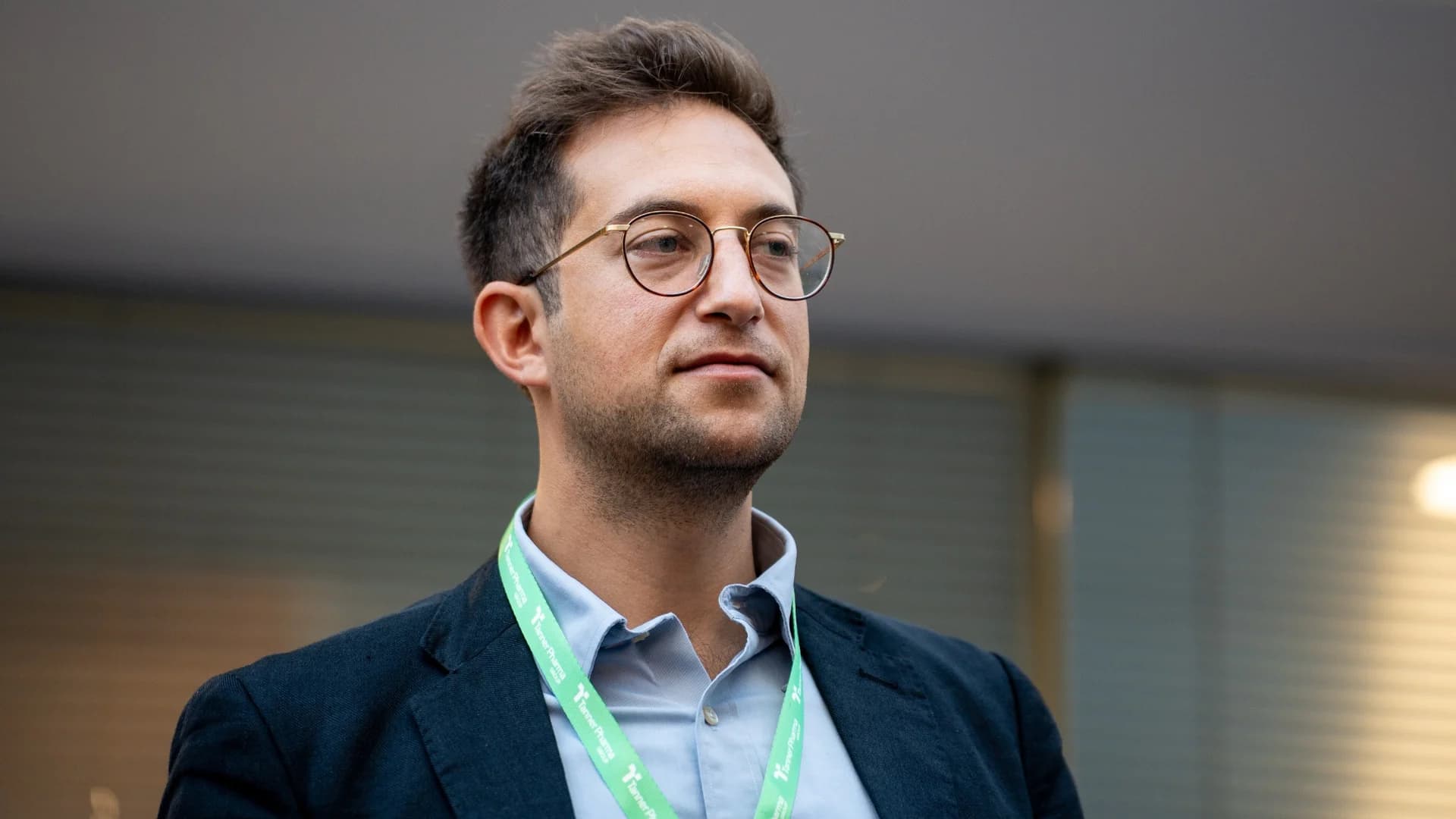 A delegate listening attentively, wearing round glasses and a lanyard