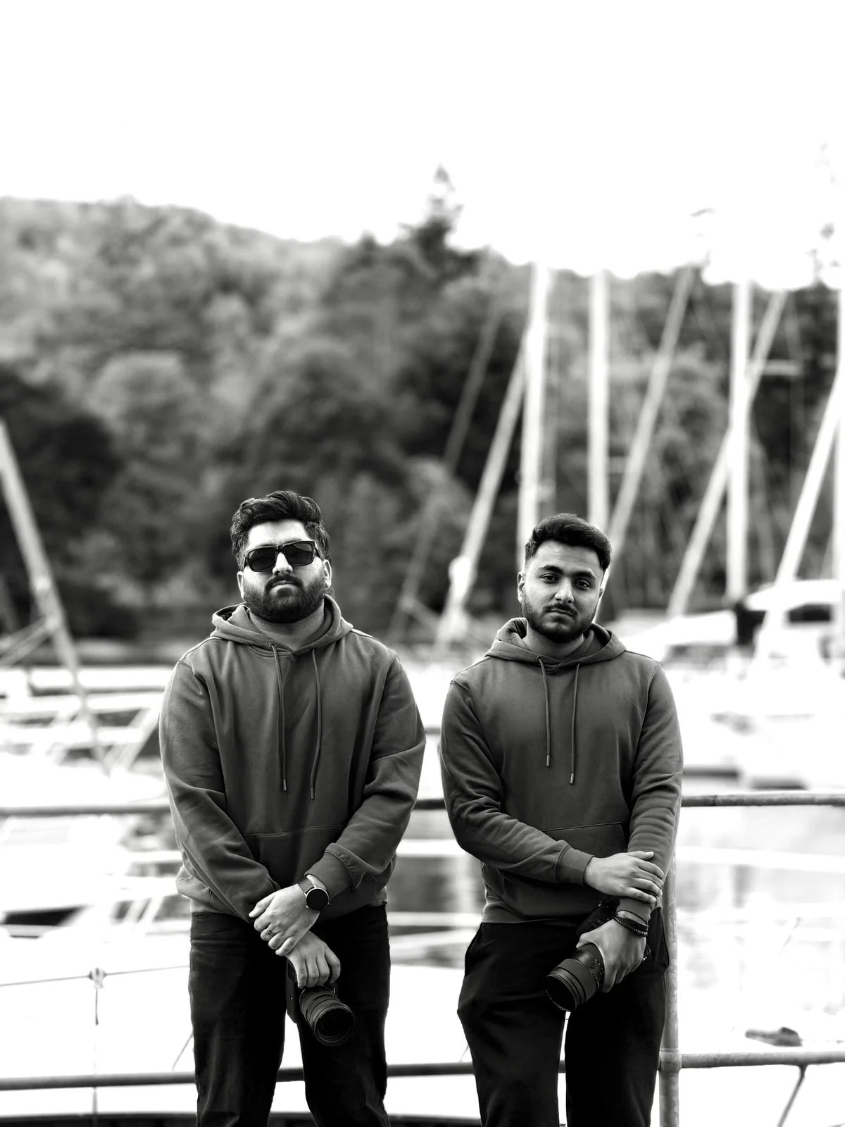 Tayyab, left, and Ali, right, the founders of LUMEX Media, holding their cameras beside a marina