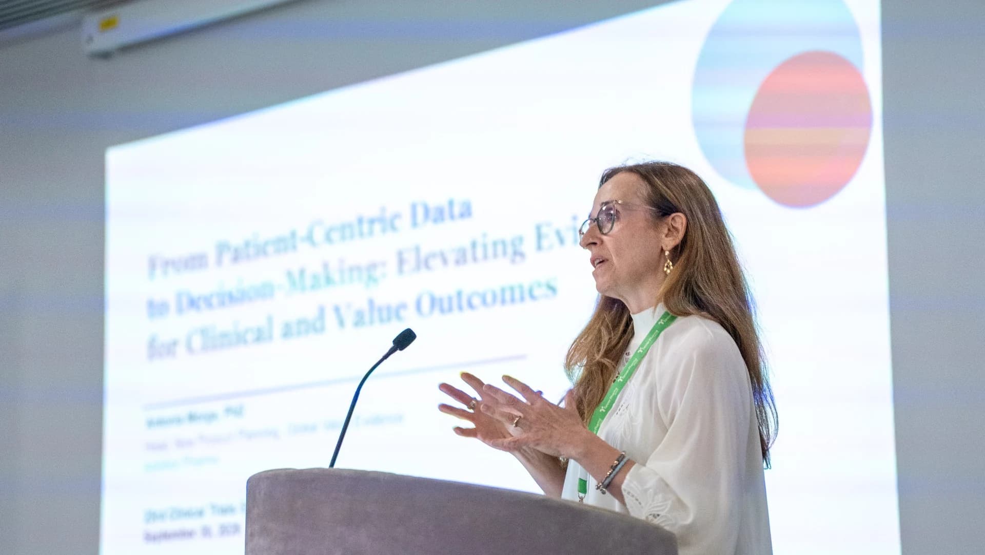 A speaker presenting beside her slides during a keynote session