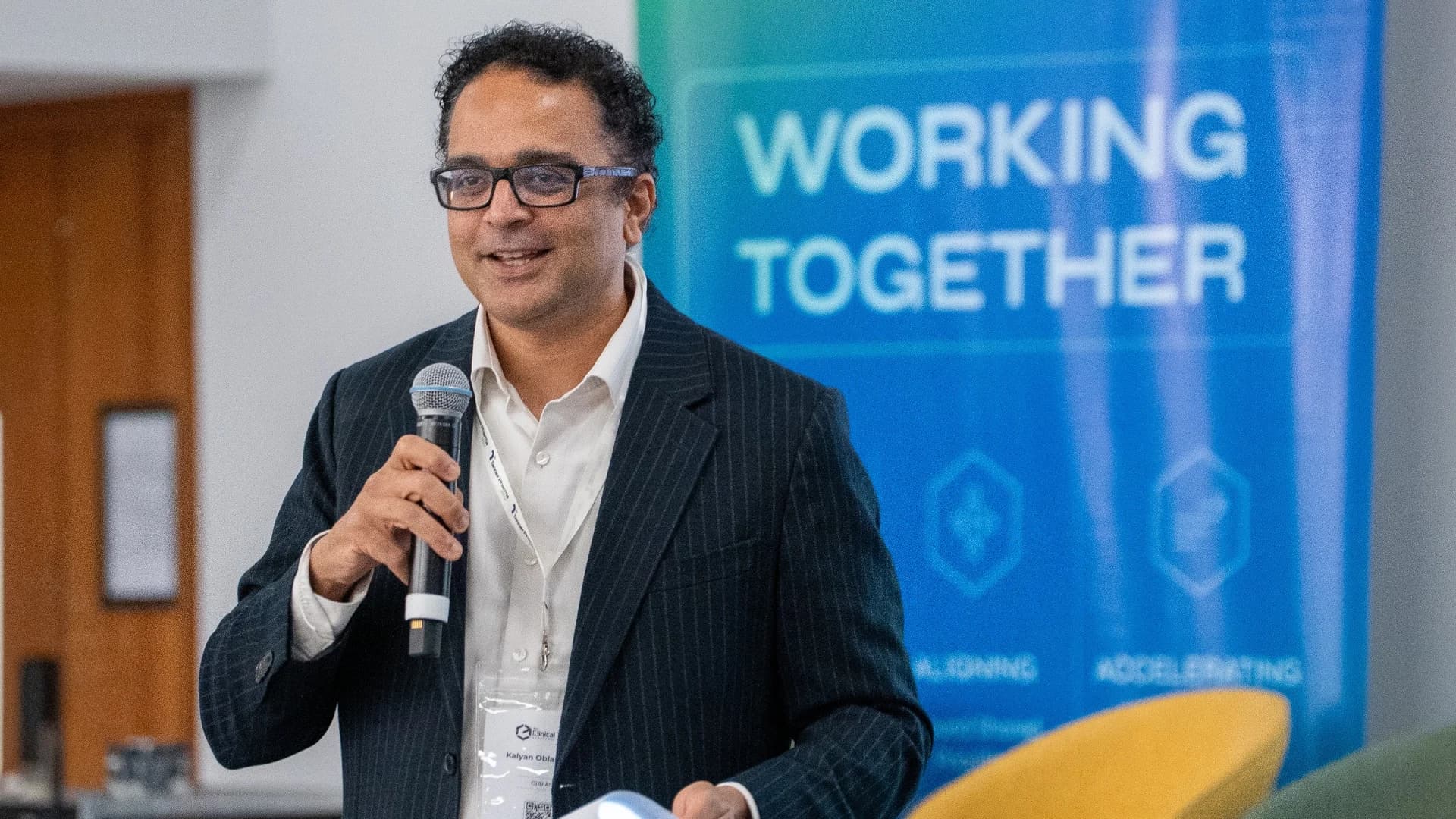 An attendee speaking into a microphone in front of a 'Working Together' banner